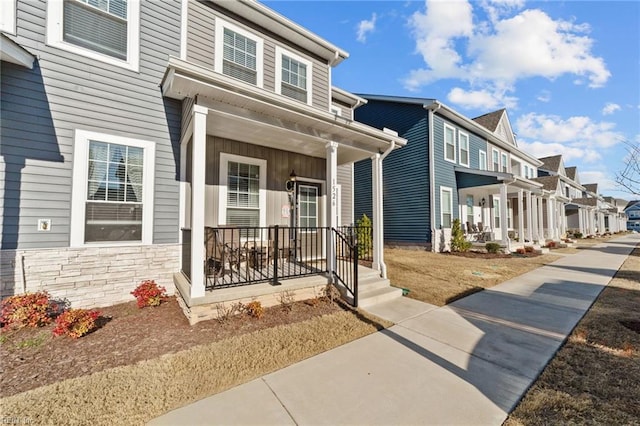 view of exterior entry with stone siding, a residential view, and a porch