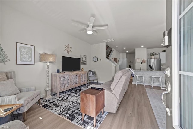 living room featuring a ceiling fan, light wood-type flooring, and visible vents