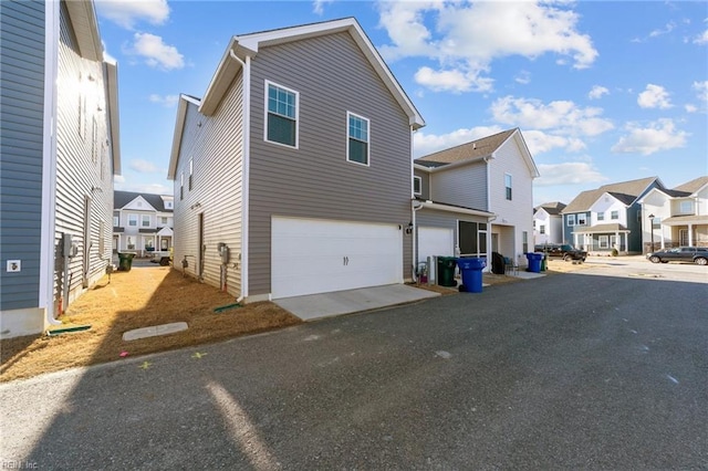 exterior space with aphalt driveway, a residential view, and an attached garage