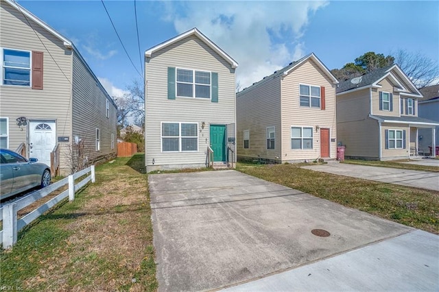 traditional home featuring entry steps, fence, and a front lawn