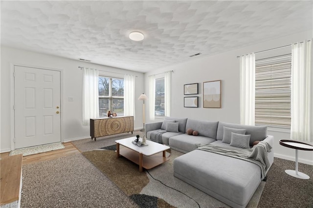 living room with a textured ceiling, baseboards, and wood finished floors