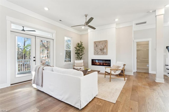 living room with light wood-type flooring, a glass covered fireplace, plenty of natural light, and stairs