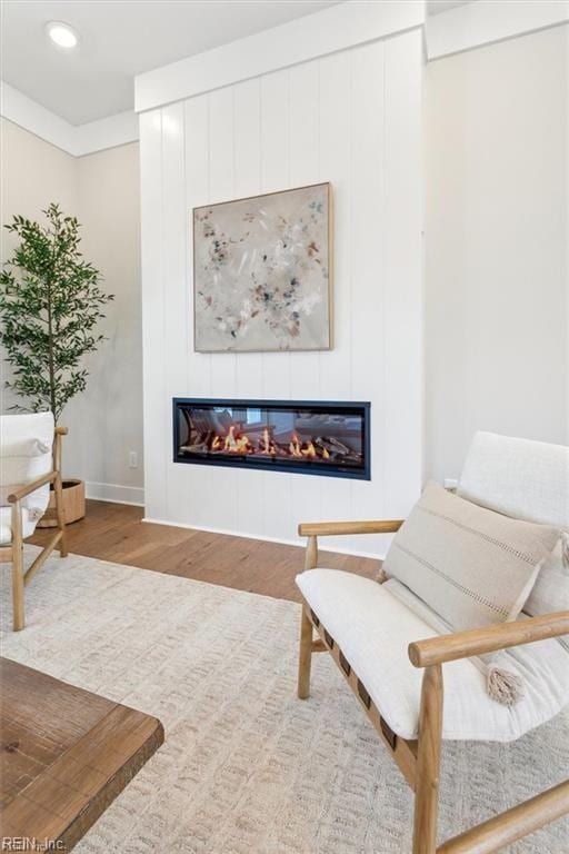 living area with wood finished floors and a glass covered fireplace