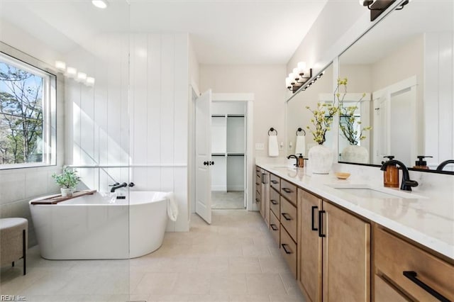 full bathroom featuring double vanity, a soaking tub, and a sink