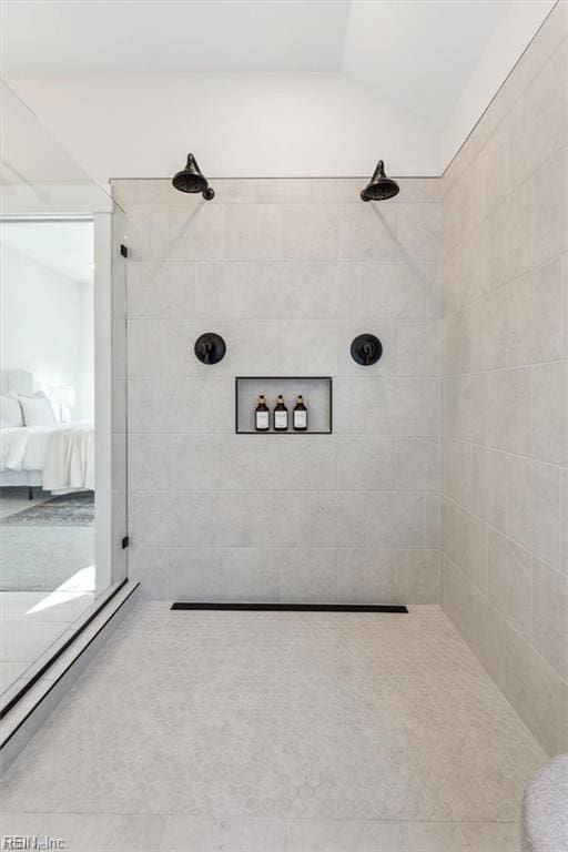 ensuite bathroom featuring vaulted ceiling, connected bathroom, and a tile shower