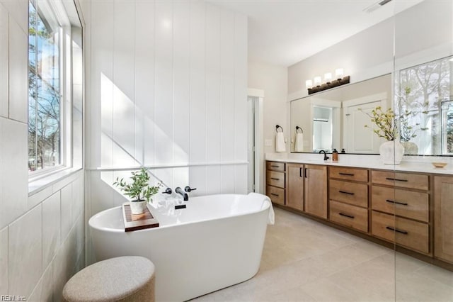 bathroom with a soaking tub, visible vents, and vanity