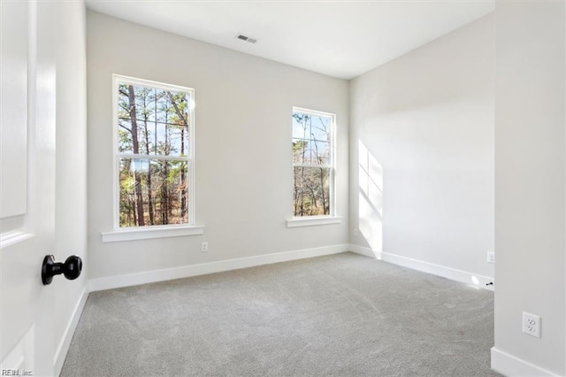 empty room with carpet, visible vents, and baseboards