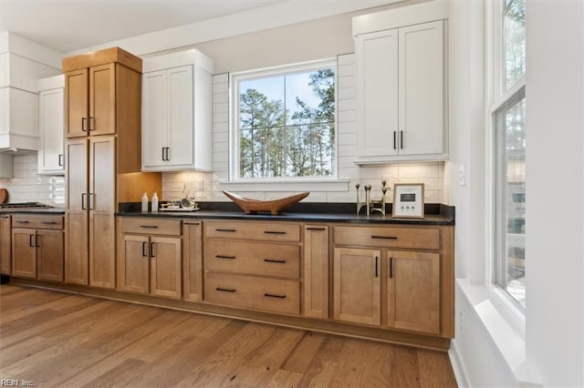 kitchen featuring tasteful backsplash, dark countertops, and light wood-style floors