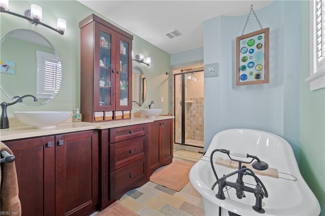 bathroom with double vanity, visible vents, a sink, a shower stall, and a freestanding tub