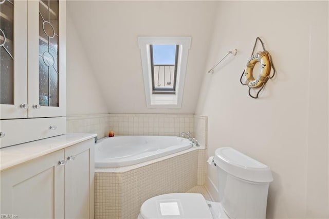 bathroom with toilet, a skylight, a bath, and vanity