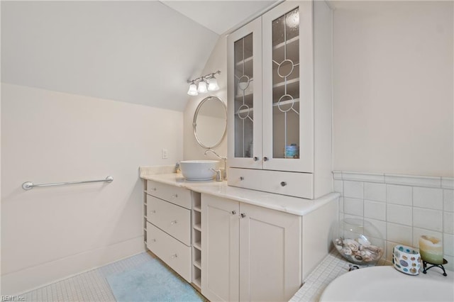 bathroom featuring vaulted ceiling, tile walls, vanity, and tile patterned floors