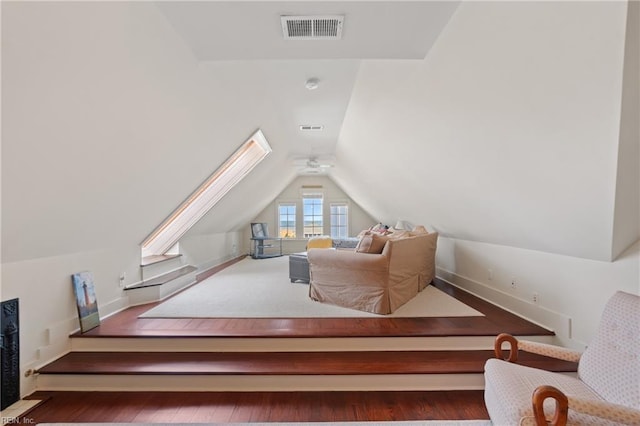 bonus room with lofted ceiling with skylight, wood finished floors, and visible vents