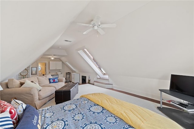 carpeted bedroom featuring lofted ceiling with skylight, visible vents, ceiling fan, and baseboards