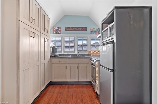 kitchen featuring dark wood-style flooring, dark countertops, appliances with stainless steel finishes, vaulted ceiling, and a sink