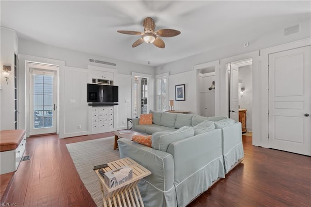 living room featuring visible vents, dark wood-type flooring, and a ceiling fan