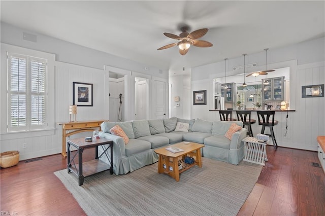 living room with wood-type flooring, visible vents, and a ceiling fan