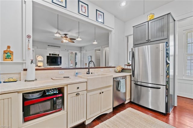 kitchen featuring dark wood-style floors, stainless steel appliances, hanging light fixtures, and a sink