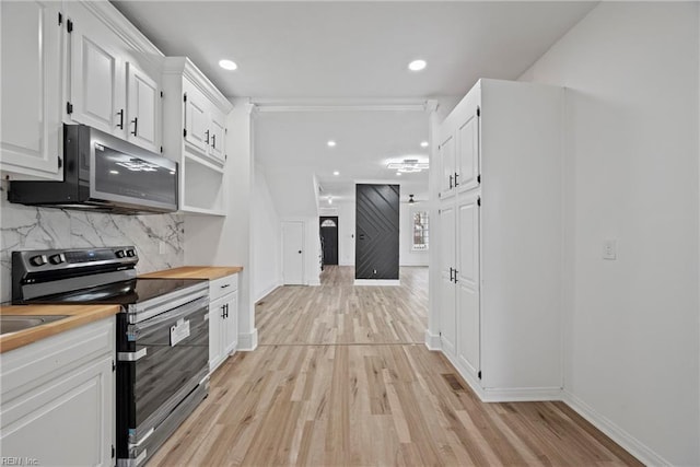 kitchen featuring light wood-style flooring, wood counters, backsplash, white cabinetry, and stainless steel appliances