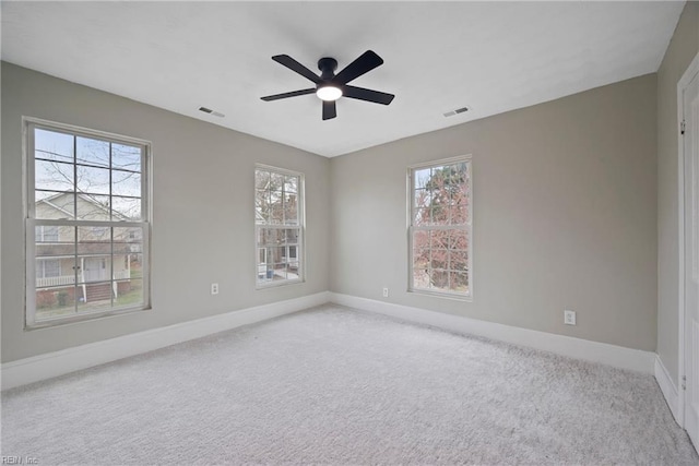 empty room with plenty of natural light, light colored carpet, and visible vents