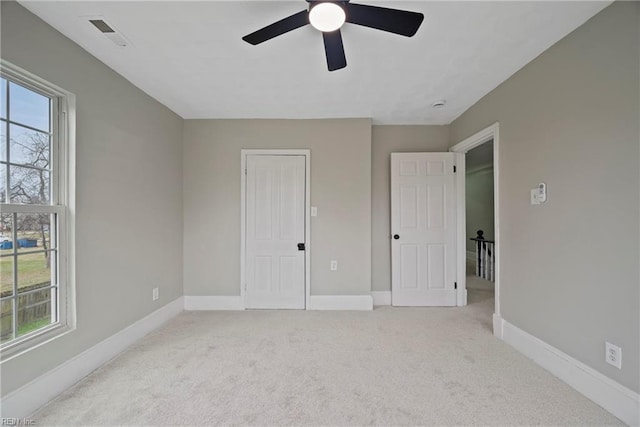 unfurnished bedroom with baseboards, multiple windows, and light colored carpet