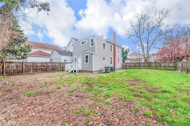 back of property featuring a yard, a fenced backyard, and a chimney