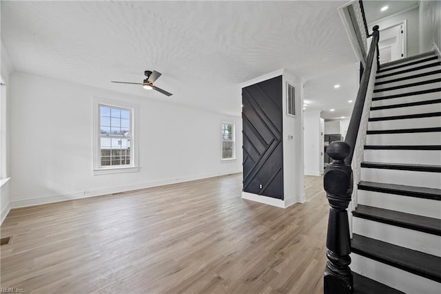 interior space featuring baseboards, ceiling fan, stairway, light wood-type flooring, and a textured ceiling