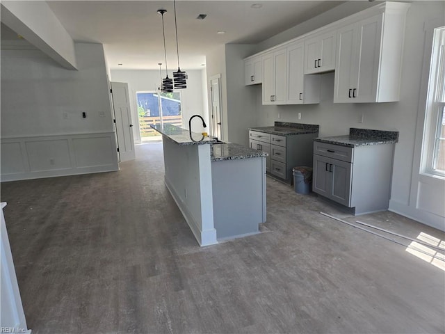 2514 Oak Ave, Newport News, VA 23607 - kitchen with a sink, wood finished floors, a center island with sink, dark stone counters, and a decorative wall
