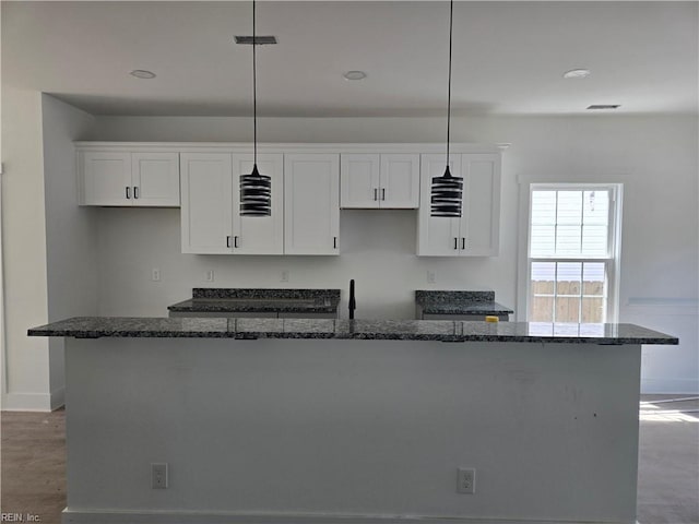 2514 Oak Ave, Newport News, VA 23607 - kitchen with a kitchen island with sink, white cabinets, baseboards, and dark stone countertops