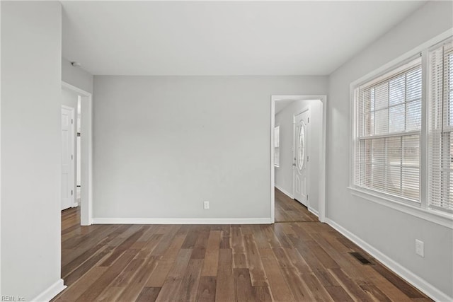 empty room with visible vents, baseboards, and wood finished floors