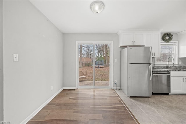 kitchen with a wealth of natural light, white cabinets, stainless steel appliances, and a sink