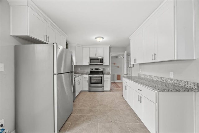 kitchen with light stone counters, appliances with stainless steel finishes, and white cabinetry