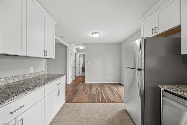 kitchen featuring light wood-style flooring, white cabinetry, stainless steel appliances, baseboards, and light stone countertops