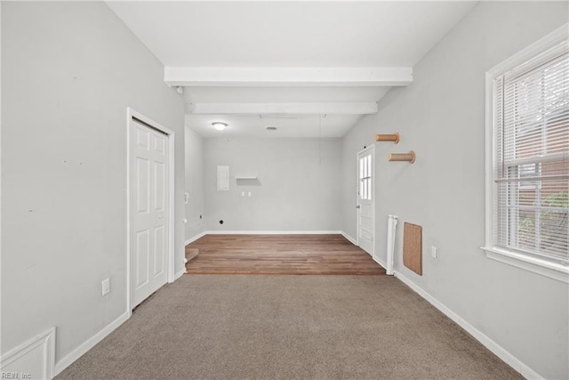 empty room with beamed ceiling, carpet, and baseboards