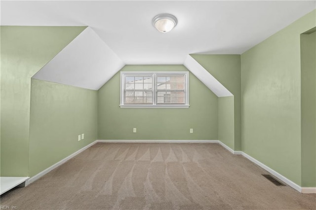 additional living space with visible vents, carpet floors, baseboards, and vaulted ceiling