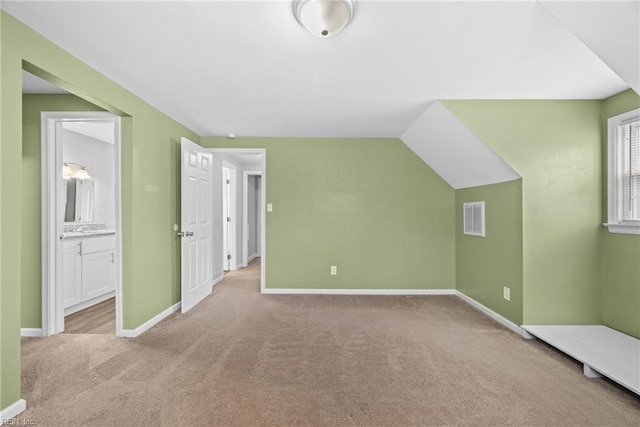 additional living space with vaulted ceiling, carpet, visible vents, and baseboards