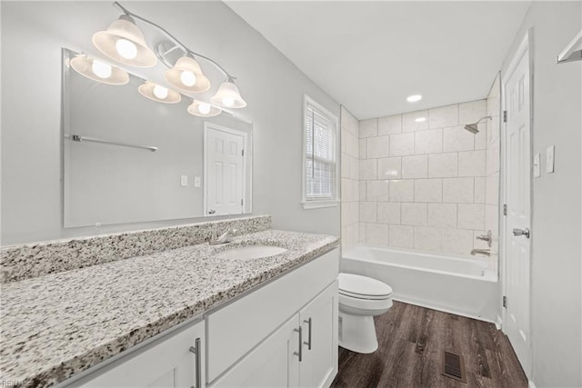 full bath with vanity, wood finished floors, visible vents, bathing tub / shower combination, and toilet