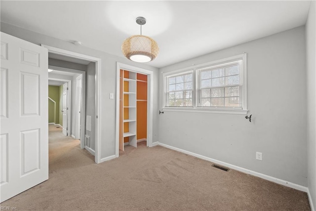 carpeted spare room with visible vents and baseboards