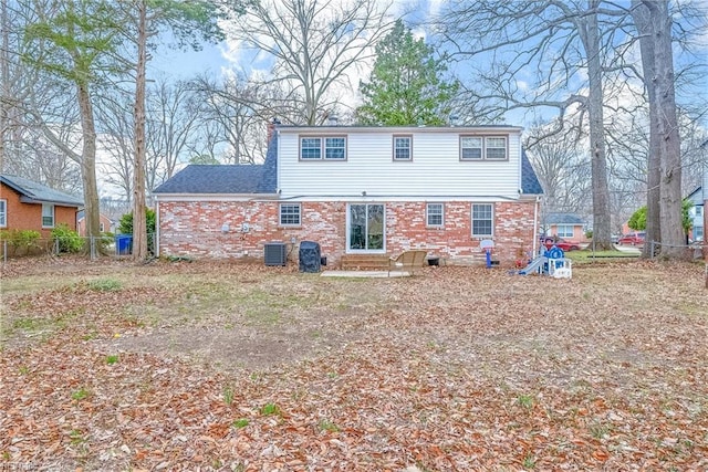 back of house featuring brick siding, a shingled roof, fence, entry steps, and central AC unit