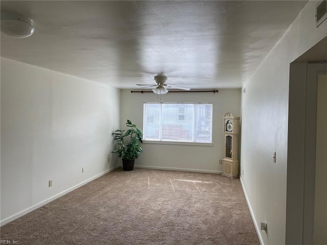 carpeted spare room featuring visible vents, baseboards, and a ceiling fan