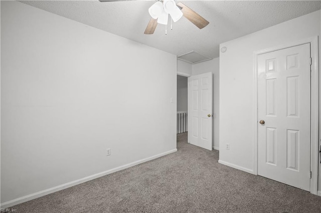 unfurnished bedroom featuring carpet floors, attic access, baseboards, and a textured ceiling