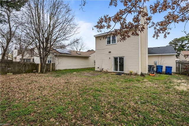 rear view of property featuring a yard, a chimney, and fence