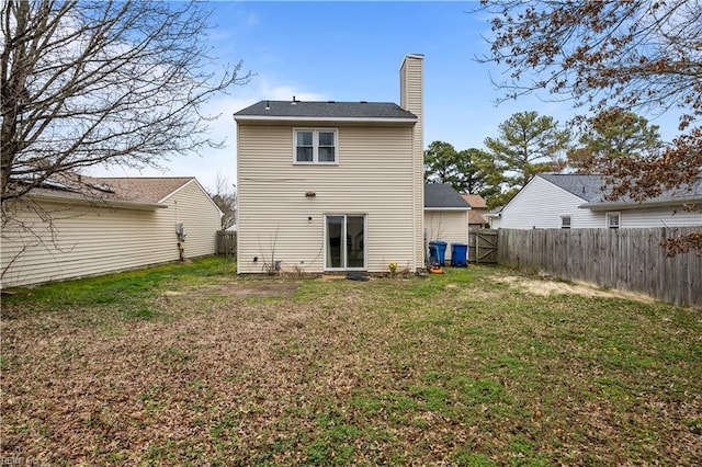 back of property featuring a fenced backyard, a lawn, and a chimney