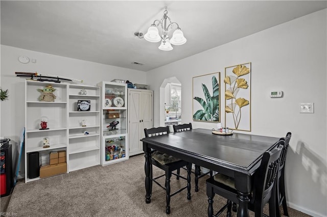 dining room featuring arched walkways, carpet flooring, and a chandelier