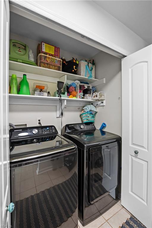 clothes washing area with light tile patterned floors, laundry area, and separate washer and dryer