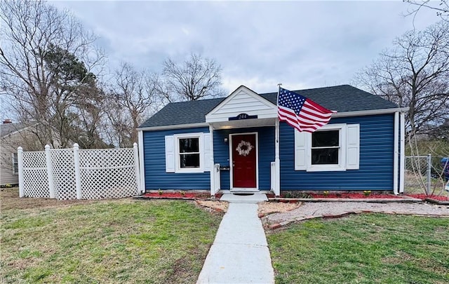 bungalow-style house with a shingled roof, fence, and a front yard