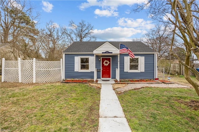 bungalow-style house featuring roof with shingles, fence, and a front yard