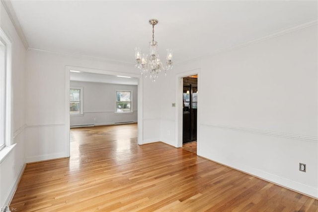 unfurnished room featuring a chandelier, light wood-type flooring, baseboards, and crown molding