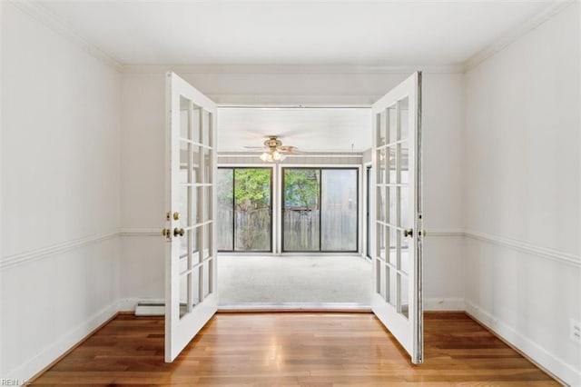 foyer entrance with crown molding, baseboards, wood finished floors, and french doors