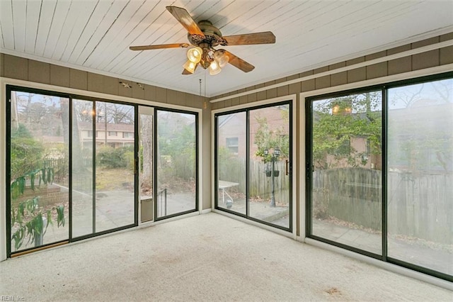 unfurnished sunroom with ceiling fan, plenty of natural light, and wood ceiling