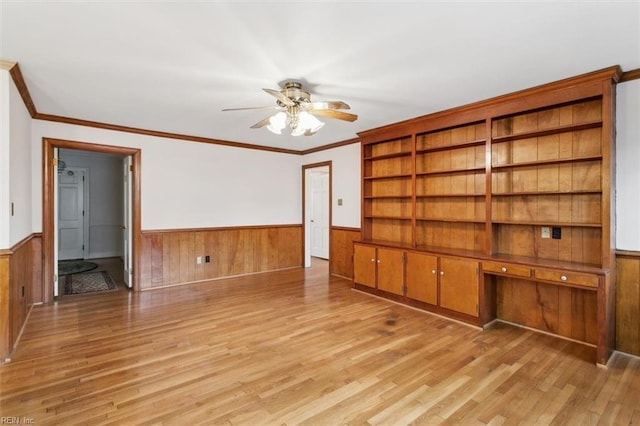 unfurnished living room featuring light wood-style floors, a wainscoted wall, and a ceiling fan